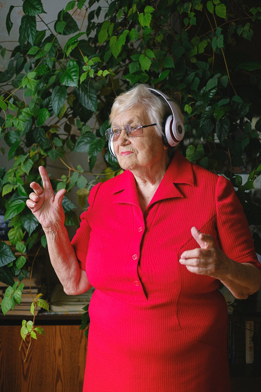 senior happy woman in red dress and headphones dancing