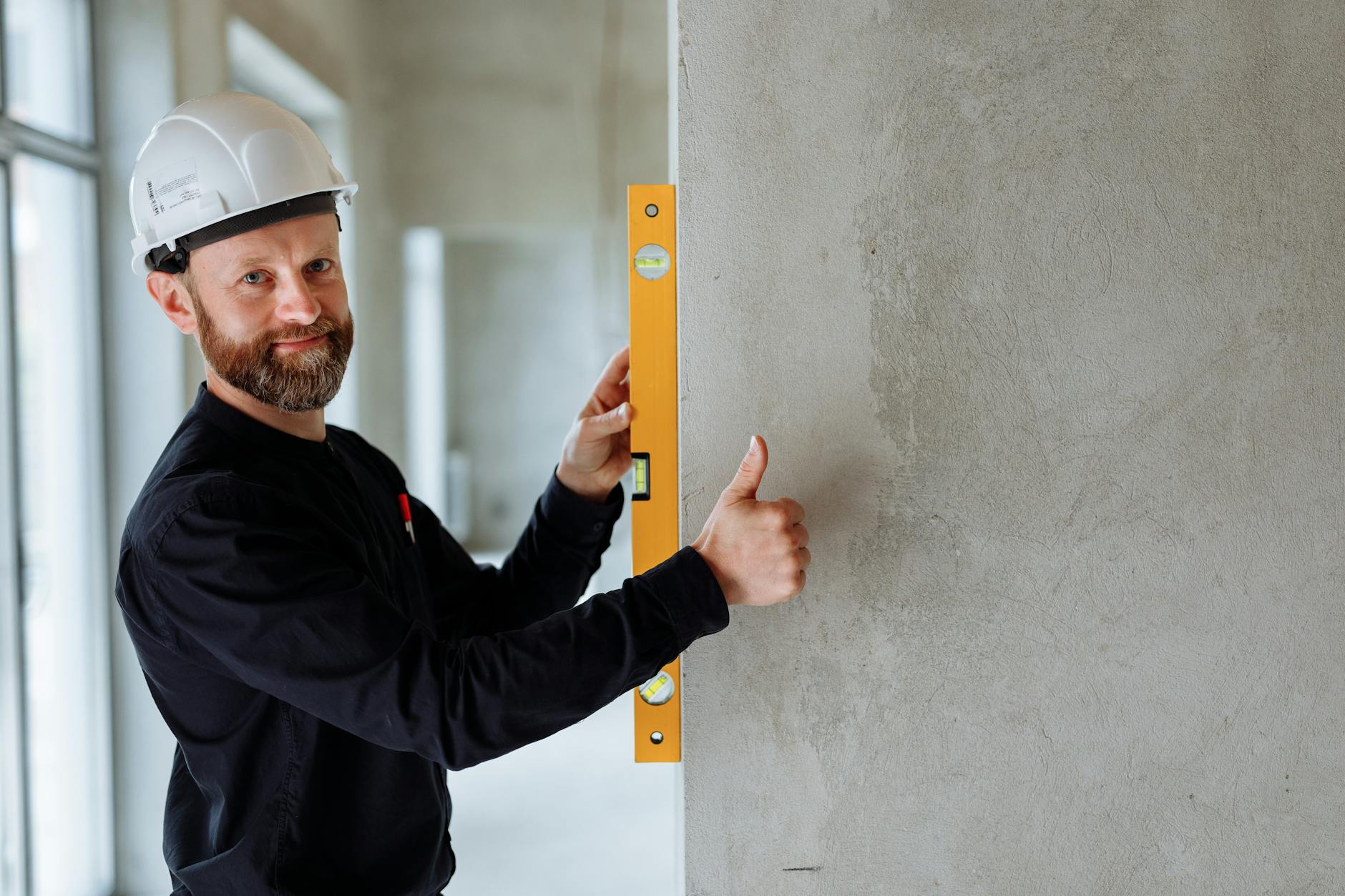 bearded man holding a yellow spirit level